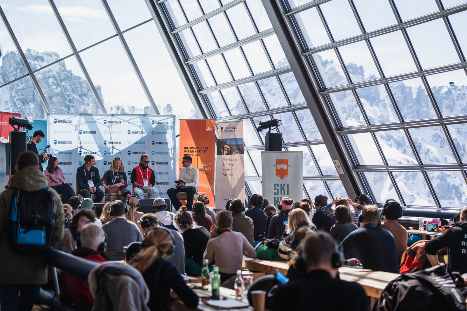 Panel discussion inside the Hoadlhaus glass dome with snowy Tyrolean peaks behind