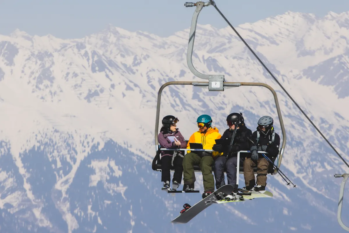 Four participants talking on a chairlift above the Tyrolean Alps